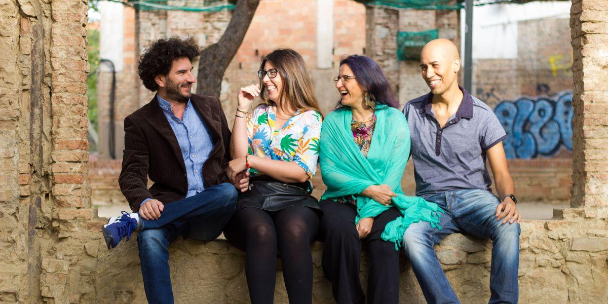 De izquierda a derecha, Javier Rey, Maui Barone, Erika Cosenza y Wenceslao Zuloaga, cofundadores de Ciempiés. Sentados sobre una pared baja de cemento y ladrillos. De fondo, desenfocado, se puede distinguir el tronco de un árbol y varias paredes de ladrillos rotos y añejados vestidas con redes contenedoras de color verde. Javier Rey, de tez blanca, cabello ondulado oscura y barba incipiente, mira de perfil a Maui Barone mientras sonríe. Viste una chaqueta de pana de color marrón oscuro, una camisa azul claro, unos pantalones vaqueros de jean y cruza su pierna izquierda sobre la derecha. Al lado, Maui Barone le devuelve la mirada sonriendo. Lleva el pelo castaño suelto y unas gafas azules. Viste una camisa diseñada con hojas de varios colores, verde, rosa, naranja. Tiene una minifalda de cuero y medias de nylon color negra. A su lado Erika Cosenza, mirando la secuencia de Javier Rey y Maui Barone, sonríe de perfil. Lleva el pelo suelto de color violeta y usa gafas. Viste un chal de color turquesa que le cubre el torso y los brazos. Tiene un pantalón negro. A su lado, Wenceslao Zuloaga, iluminado por un rayo de sol, sonríe. Viste un polo color azul, unos pantalones vaqueros de jean.